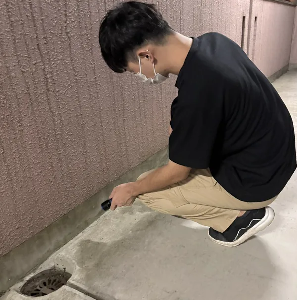 捜索員 木原（建物まわりの隙間をライトで確認）